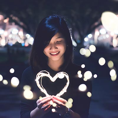 Woman smiling and holding an illuminated heart