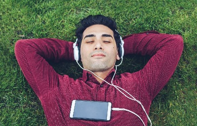 man with earbuds, relaxing on grass