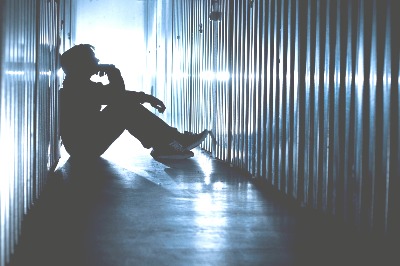 Depressed man sitting against wall